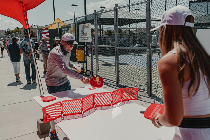 Testers play Pepper Pong on a table at an event. The game is said to be playable on any flat surface, from the hood of a car to a dinning room table.